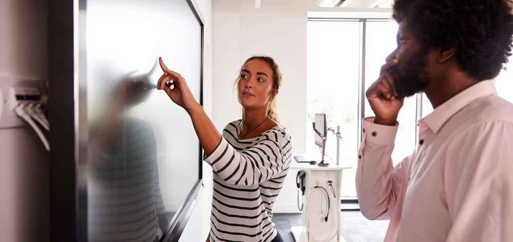 Student And Tutor Discuss Project On Interactive Whiteboard