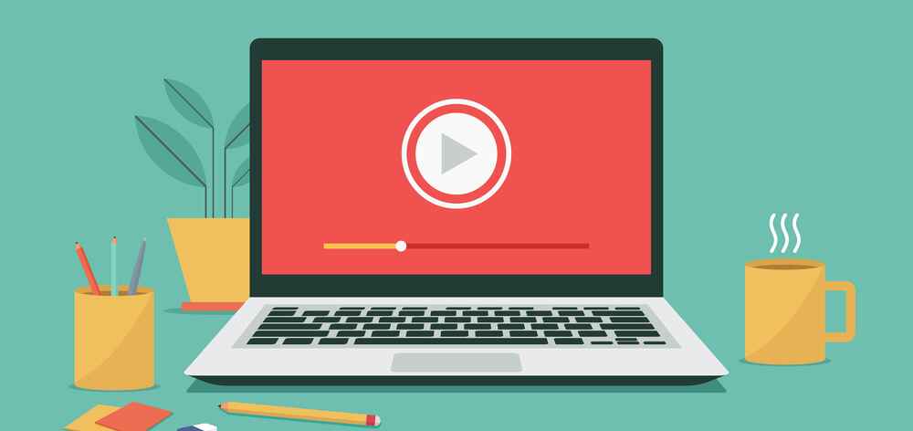 A laptop on a desk displays a video play button. Nearby are a steaming coffee mug, pencils in a cup, eraser, and sticky notes, with a plant in the background.