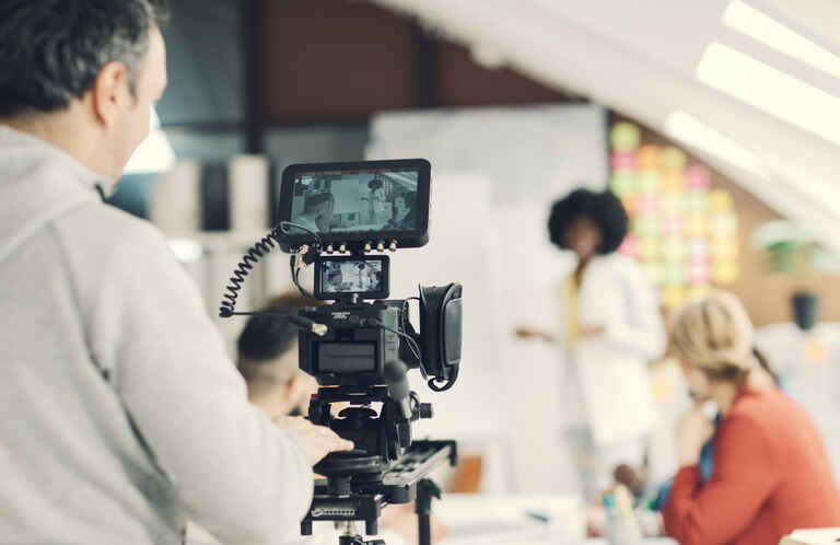 videographer filming a teacher teaching in front of a classroom