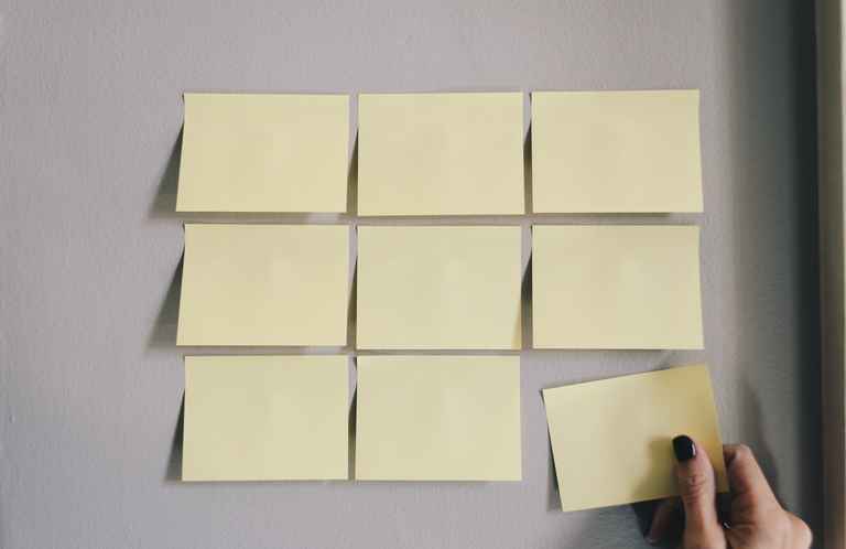 A photo of a person putting post-it notes on a wall