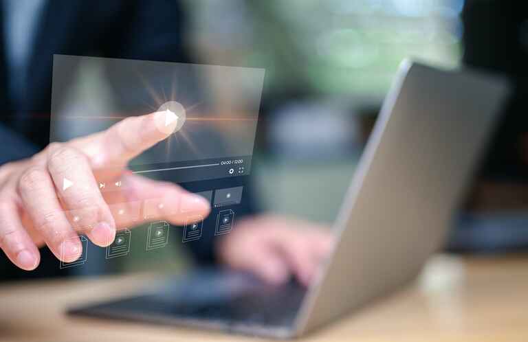 Photo of someone working on a laptop and pressing the play button on an interactive video