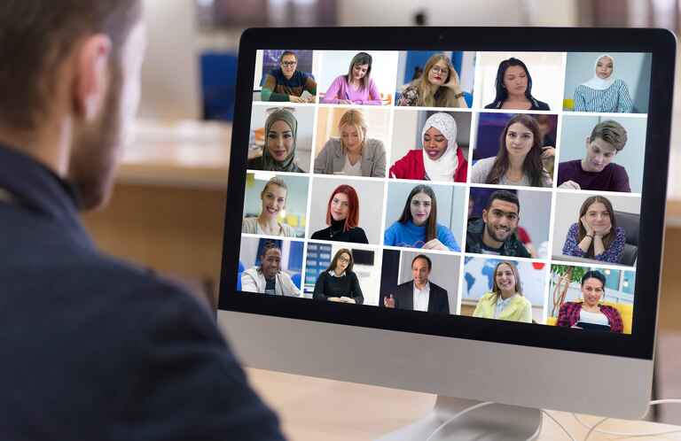 Teacher with computer having video conference chat with student and class group.