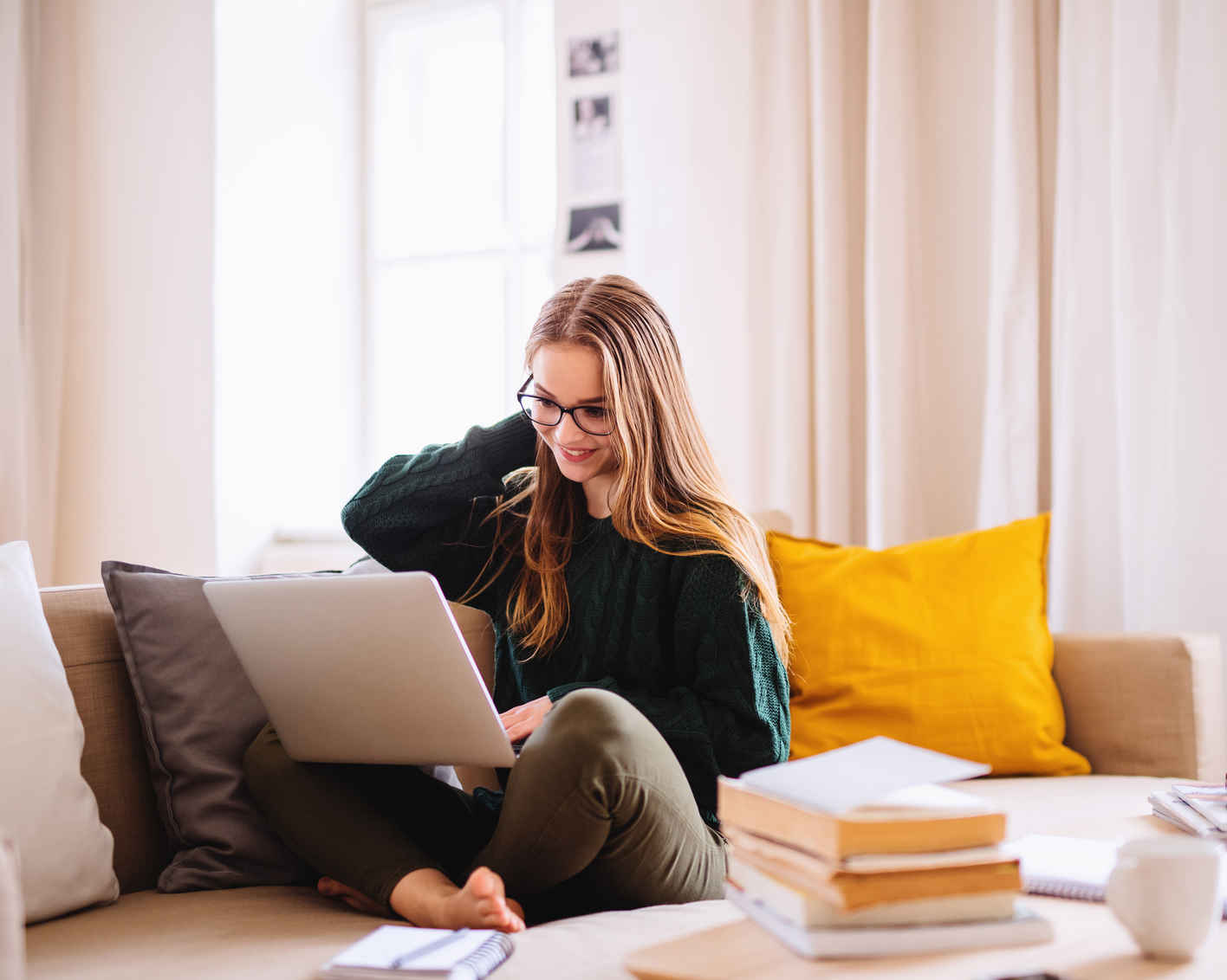 A young female student sitting on sofa, using laptop when studying