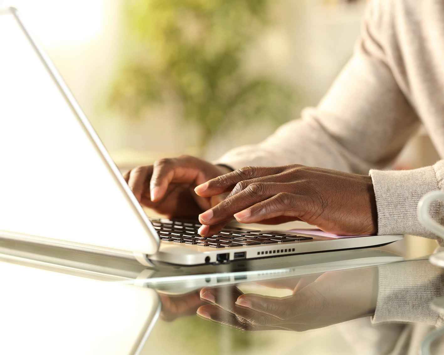 African American man's hands typing on a laptop at home