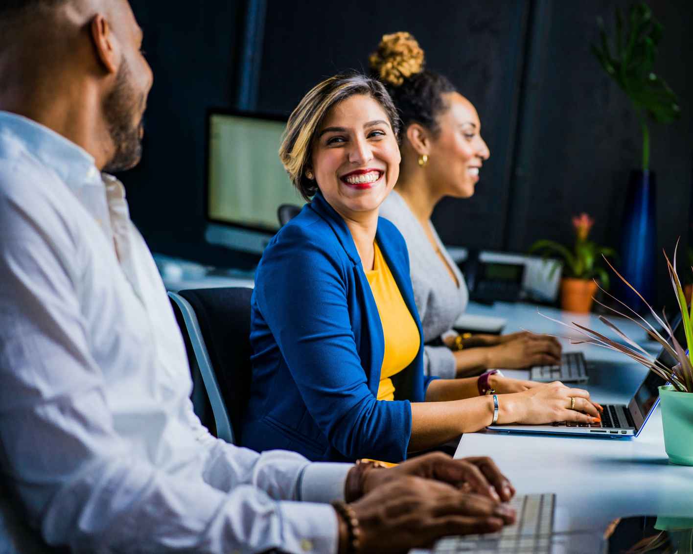 team of diverse coworkers laughing together at a workstation