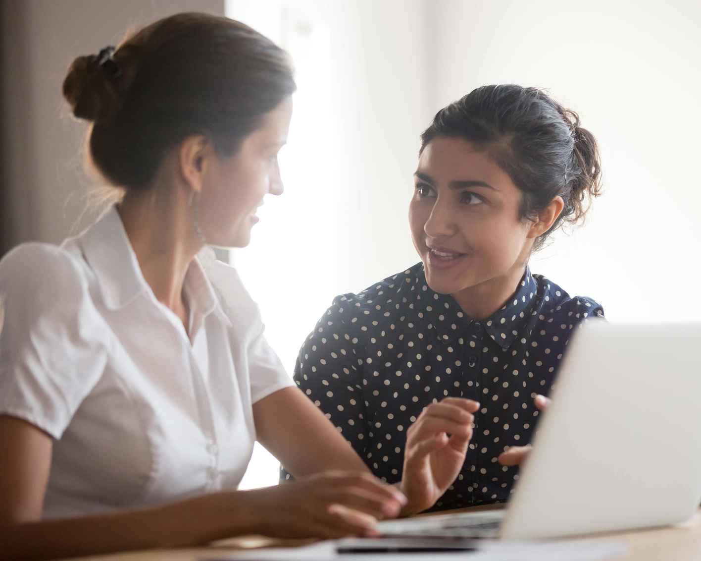 Two women talking while looking at a laptop computer