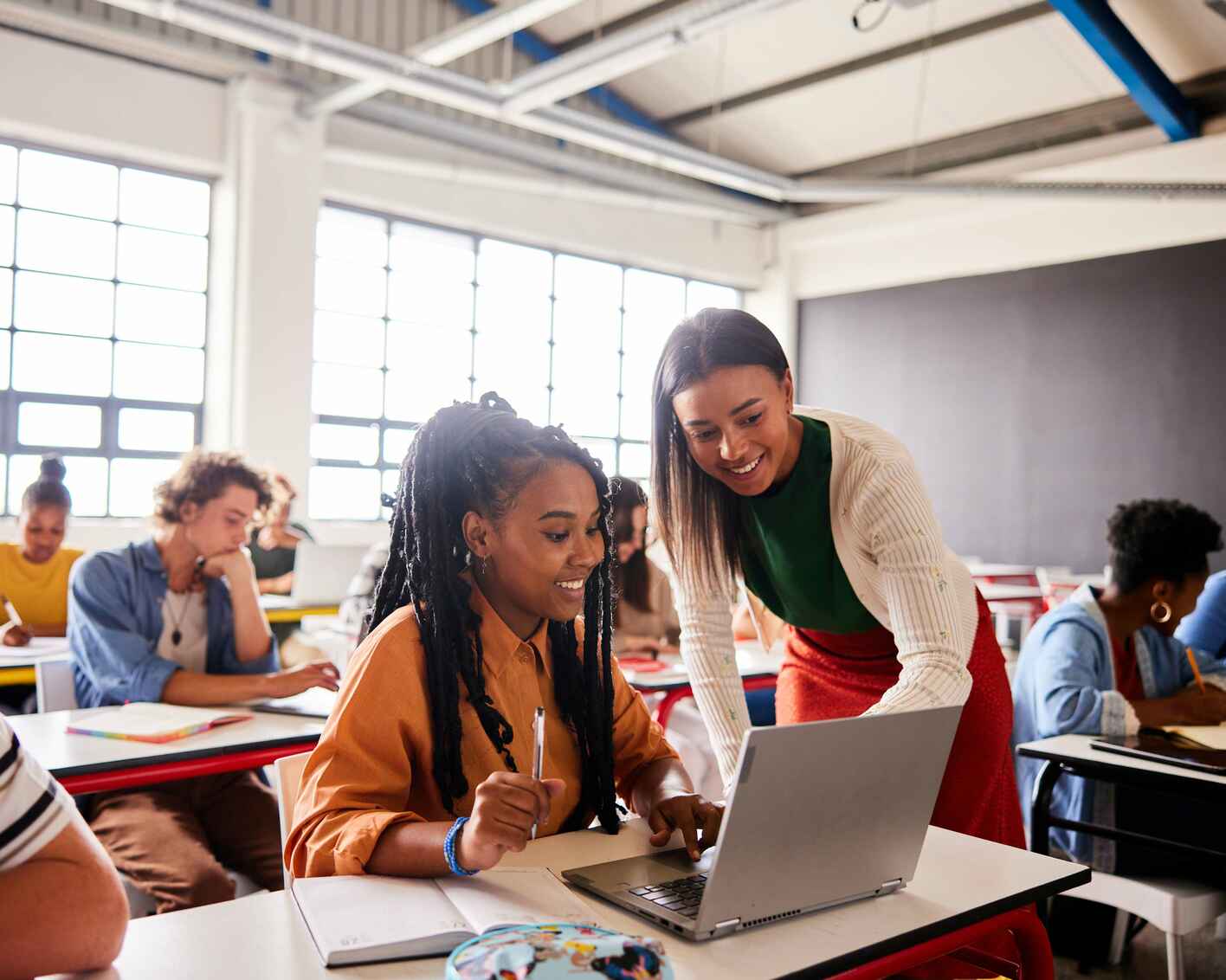 Photo of a female instructor assisting a female student on her laptop in a classroom setting