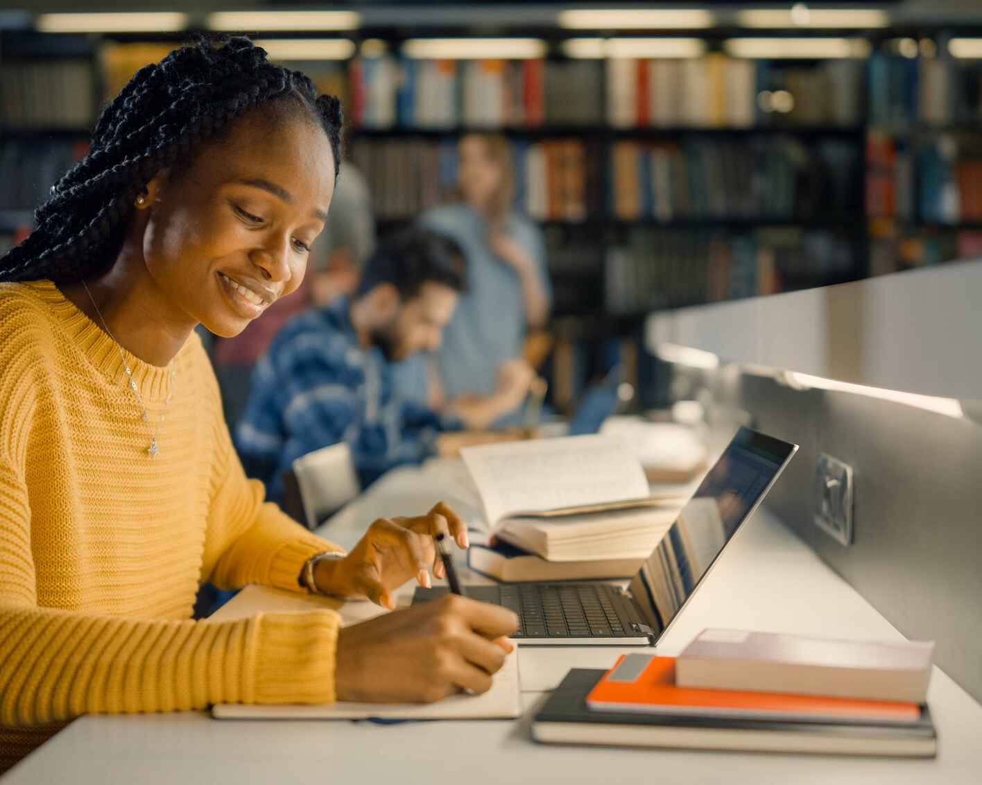 Female student writing in her notebook in a library