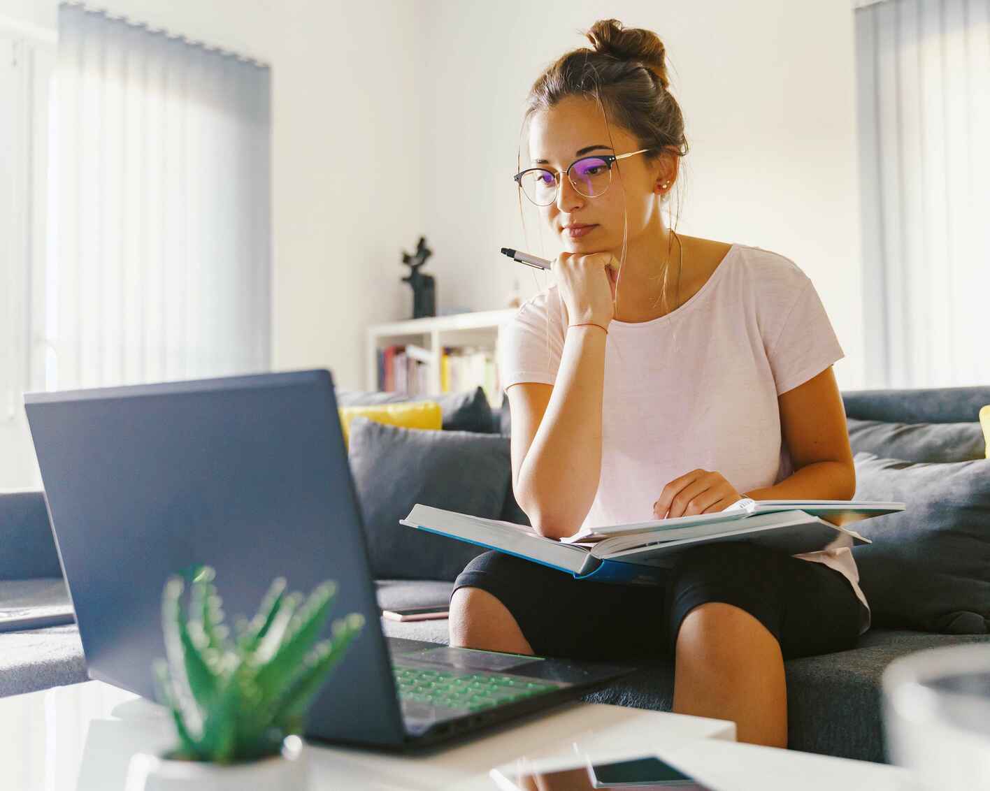 Front view of young woman studying in front of a laptop computer at home