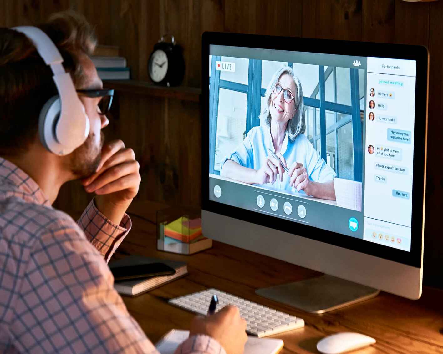 Male student wearing headphones interacting with his instructor in a live synchronous session