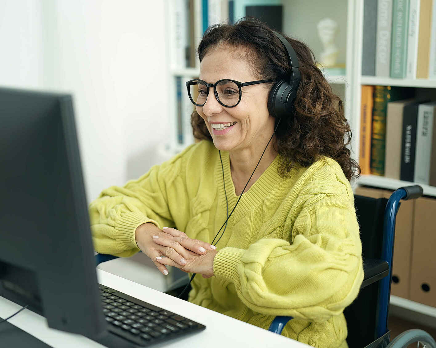 Middle age hispanic woman teacher using computer sitting on wheelchair at library university