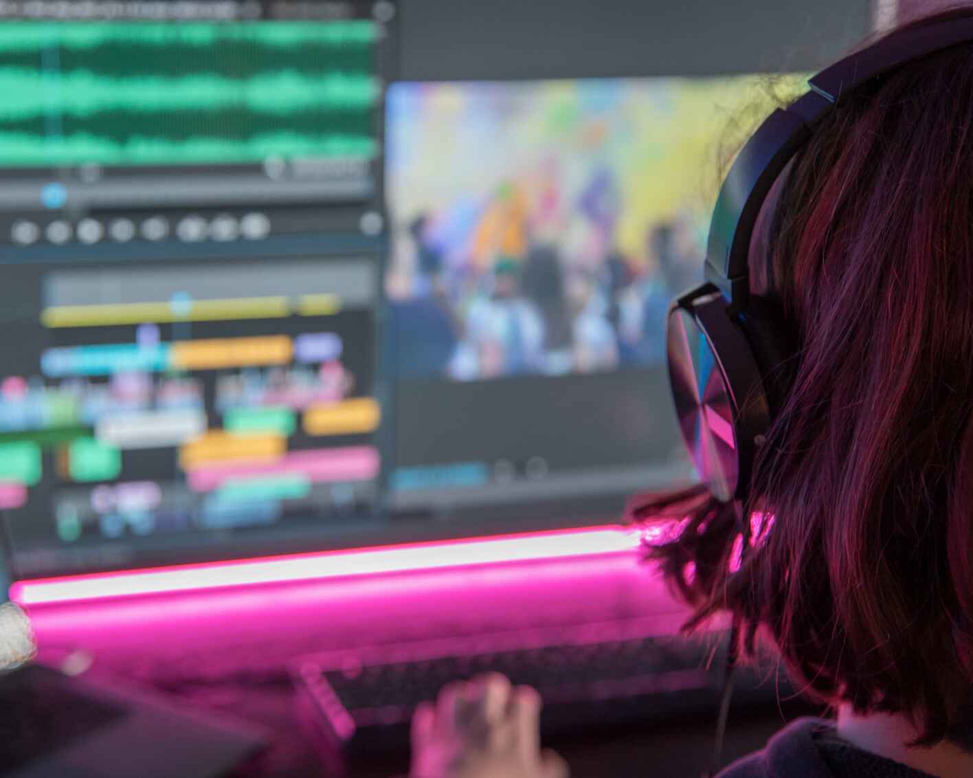 An over the shoulder shot of a woman editing videos on a computer screen.