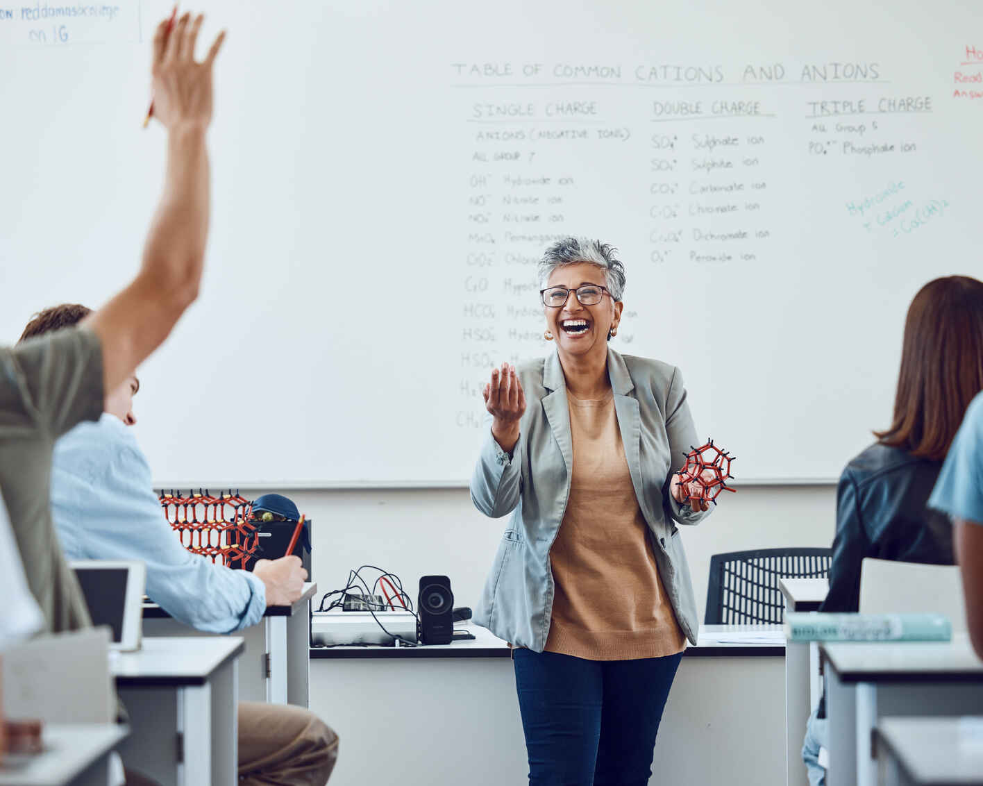 instructor laughing as she engages with her students at the front of the class
