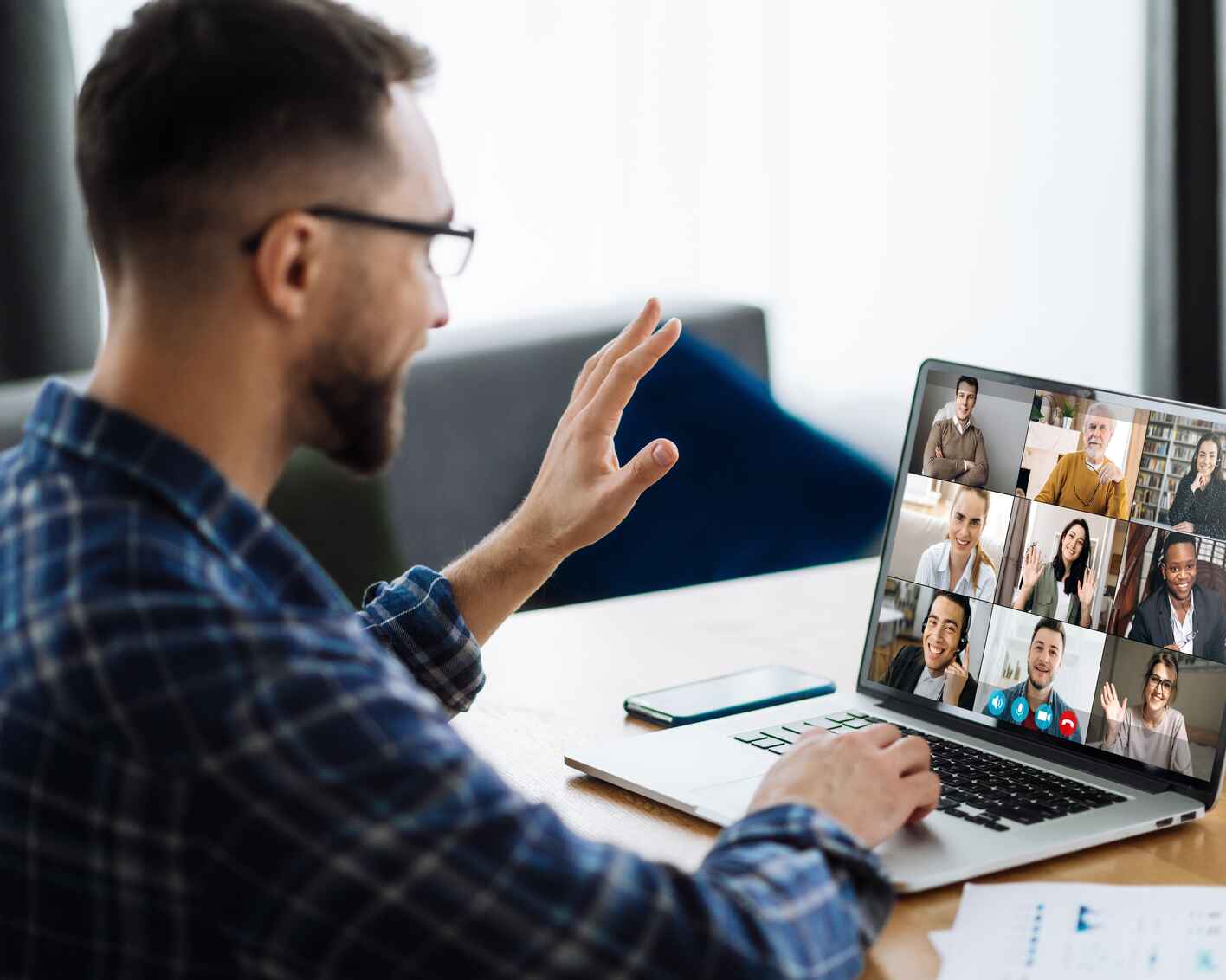 person waving hand and greeting colleagues during video conference