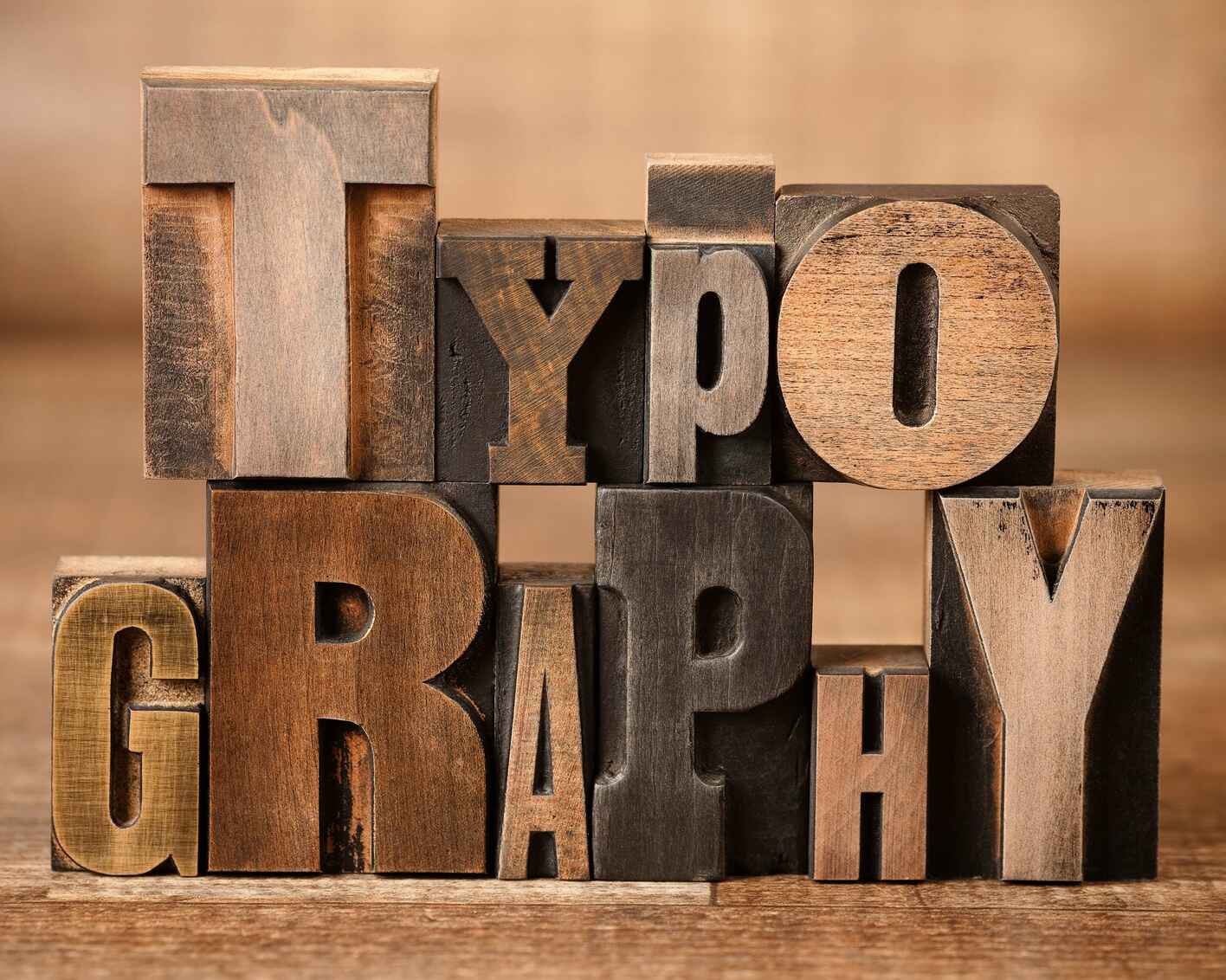 A stack of vintage wooden printing blocks arranged to spell “TYPOGRAPHY” in different fonts and sizes, creating a rustic and artistic visual effect.