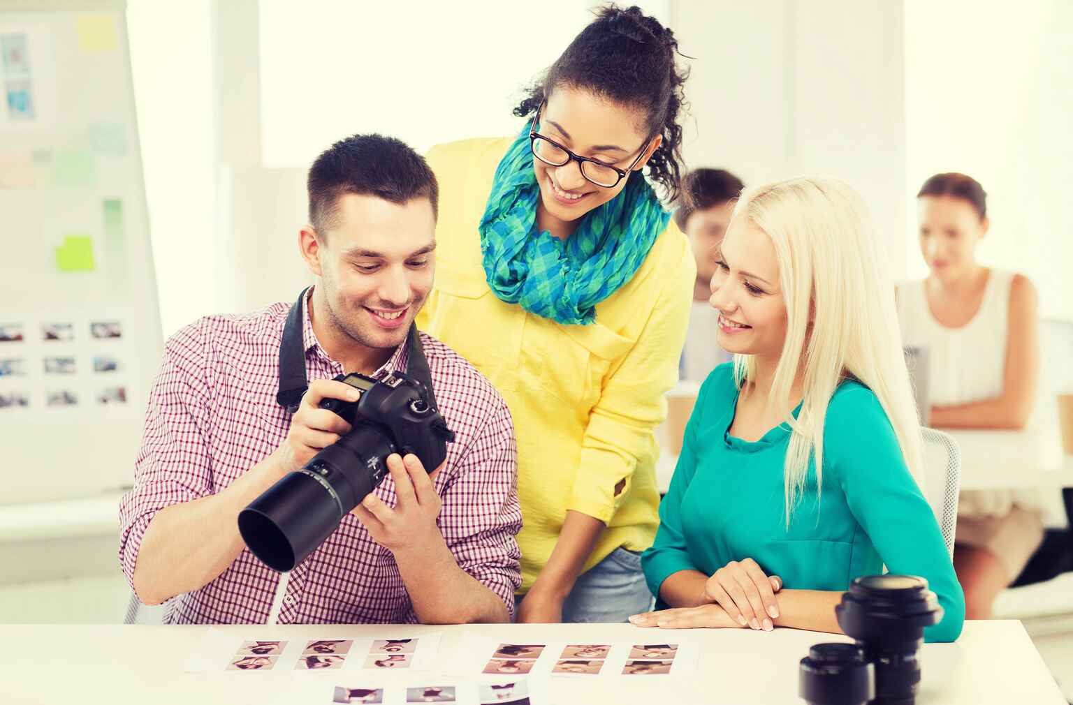 Photo of a smiling team with a camera working in an office