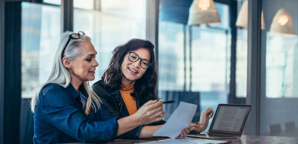 two female professionals working together at a desktop 