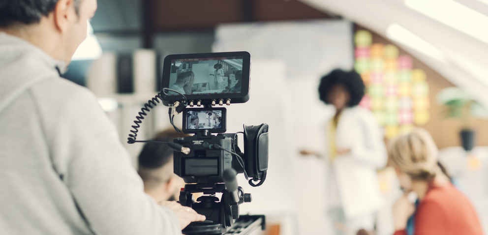 videographer filming a teacher teaching in front of a classroom