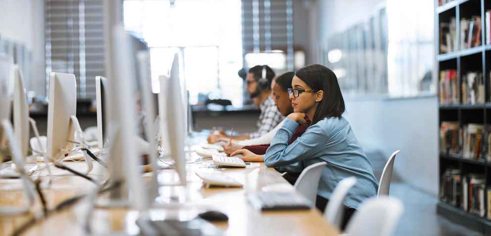 Photo of a group of university students working on computers in the library at campus