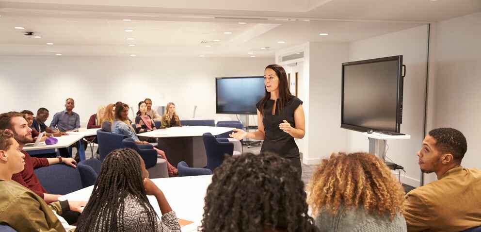 Female teacher addressing university students in a classroom