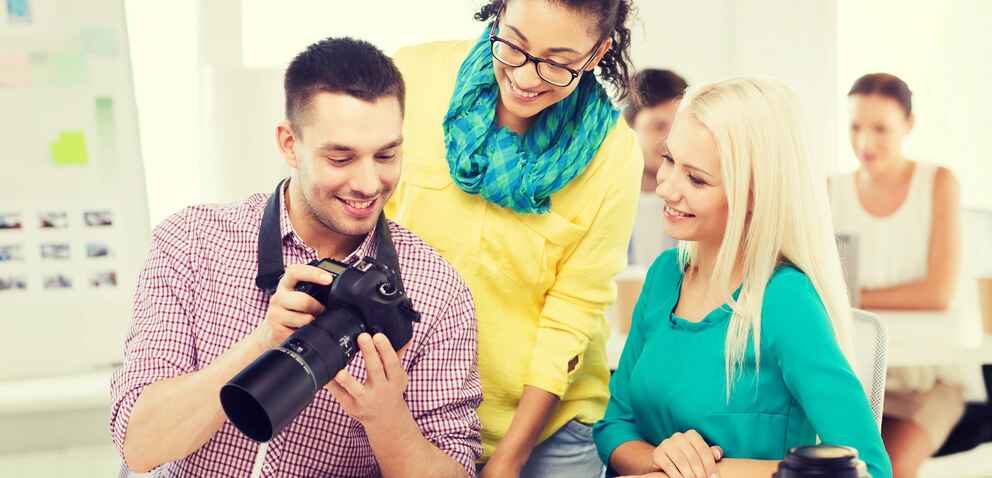 Photo of a smiling team with a camera working in an office
