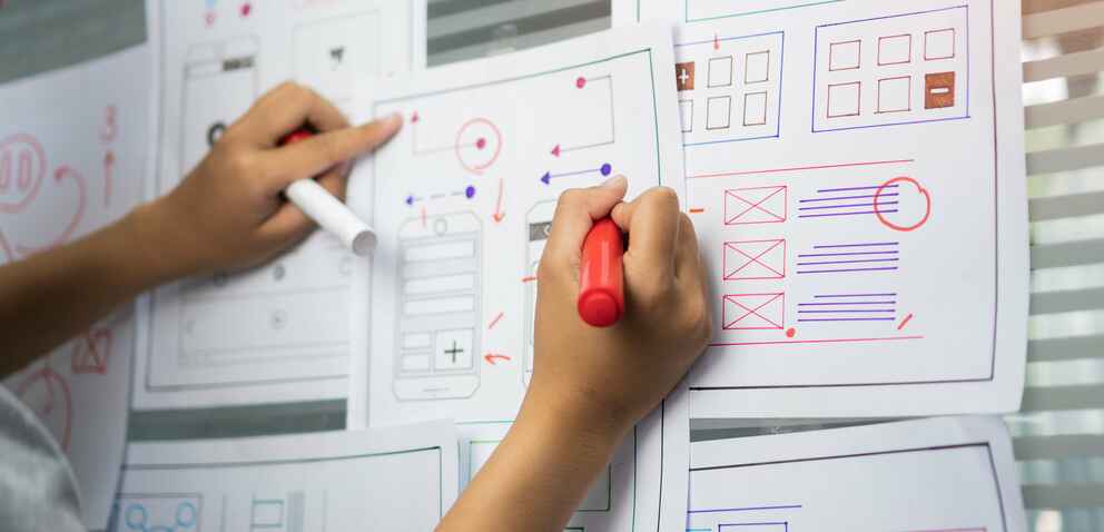 Photo of a woman creating wireframes with pen and paper