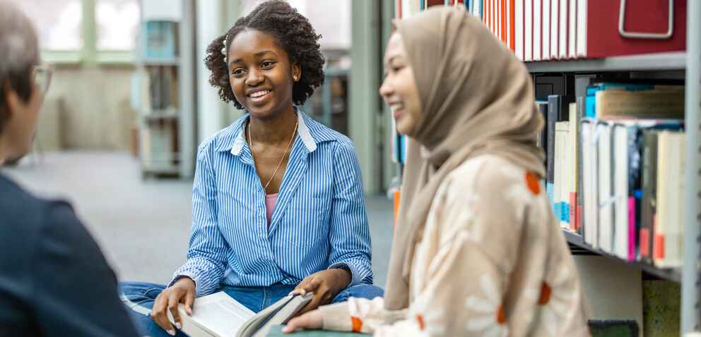 Group of students sitting in a library and studying together