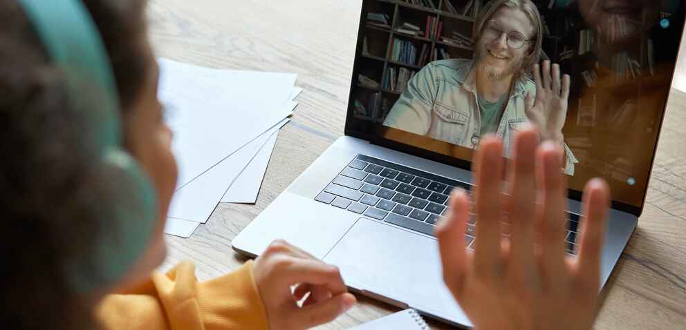 Photo of a female student and male teacher interacting in a virtual meeting