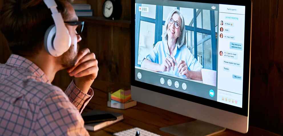 Male student wearing headphones interacting with his instructor in a live synchronous session