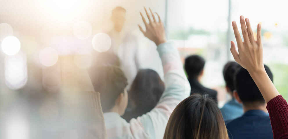 hands raised in a classroom of adult learners