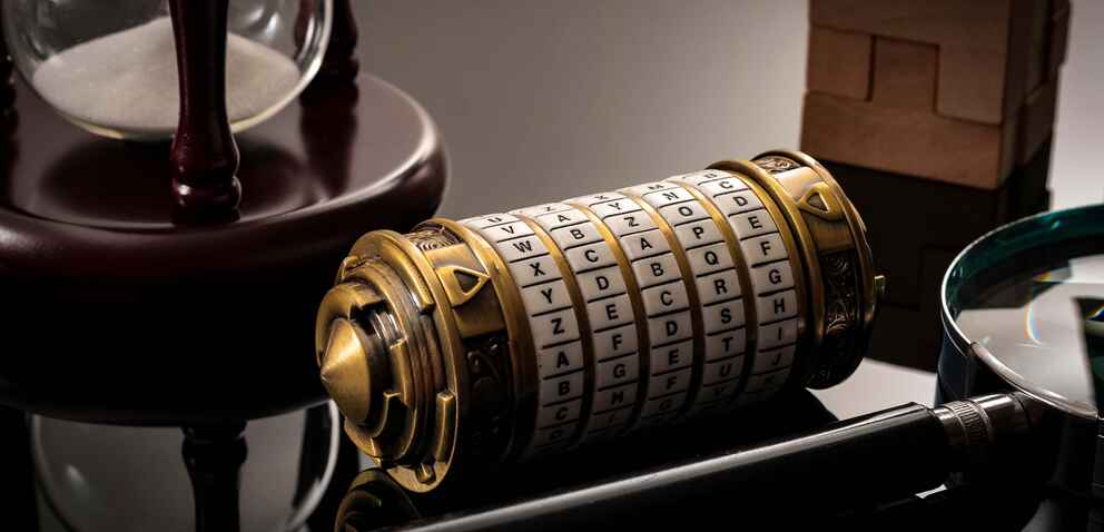 A close-up photograph of a cryptex, an hourglass, and a magnifying glass