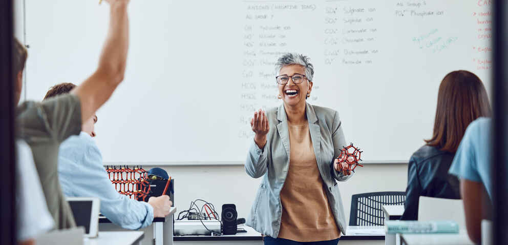 instructor laughing as she engages with her students at the front of the class