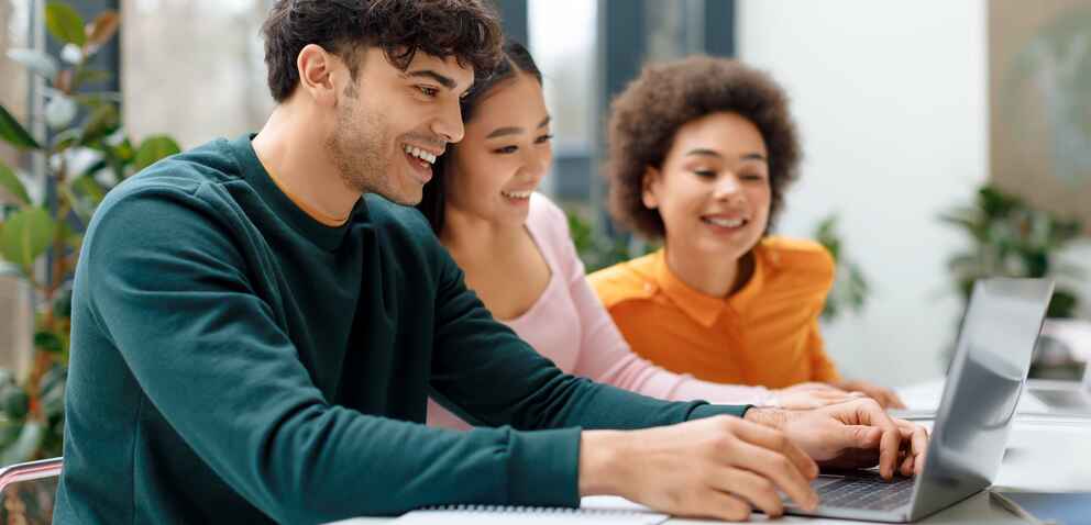 Three people looking at laptop