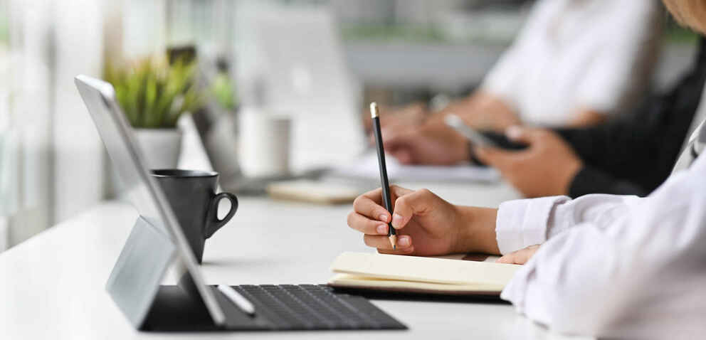 Close-up view of young businesswoman working on his plan writing the idea on notebook with digital tablet.